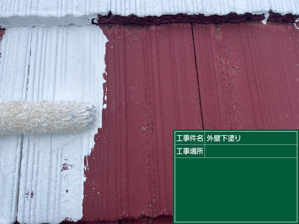 「ローラーを使い、下塗り材を均一に塗布している職人の手元が写っています。」